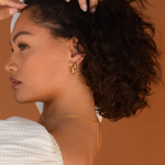 Close-up of a woman with curly hair showcasing the 'Trina Hoops' 14K Gold Plated earrings