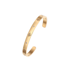 A gold-colored cuff bangle bracelet with white cubic zirconia stones set around it.