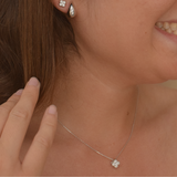 Sterling silver clover stud earrings presented next to a matching necklace