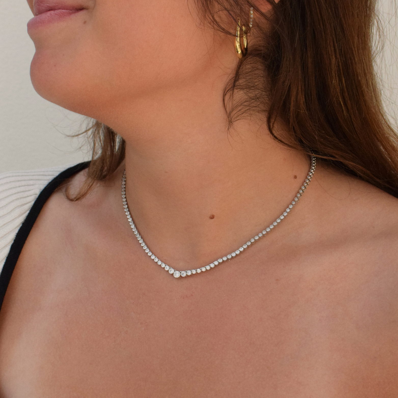 Elegant sterling silver tennis necklace with graduating diamonds worn by a woman