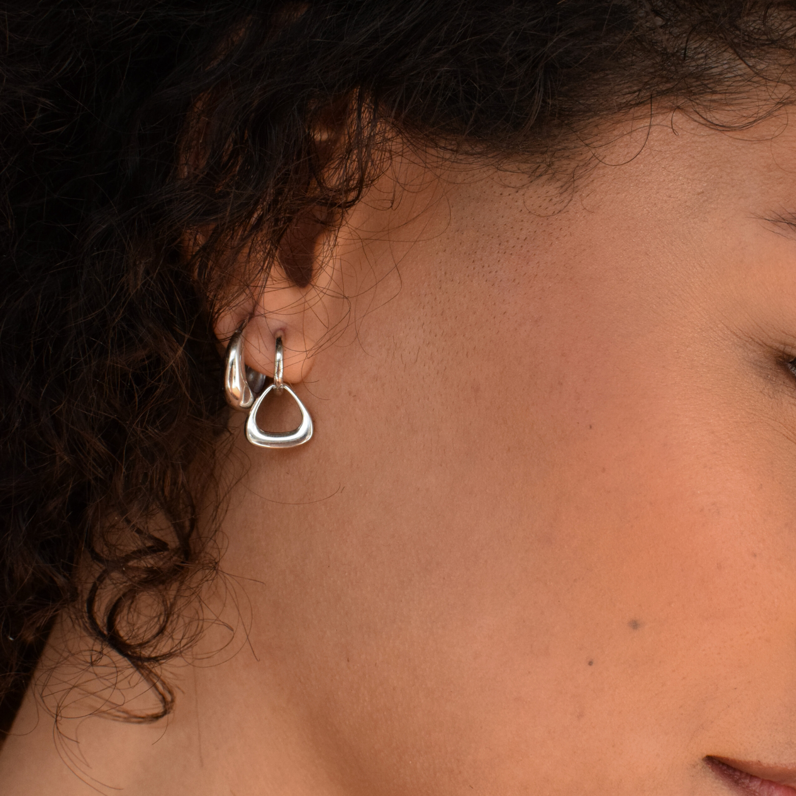 Detail shot of a woman wearing Isla Hoops sterling silver earrings