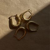 A set of three 'Trina Hoops' 14K Gold Plated earrings arranged on a wooden surface