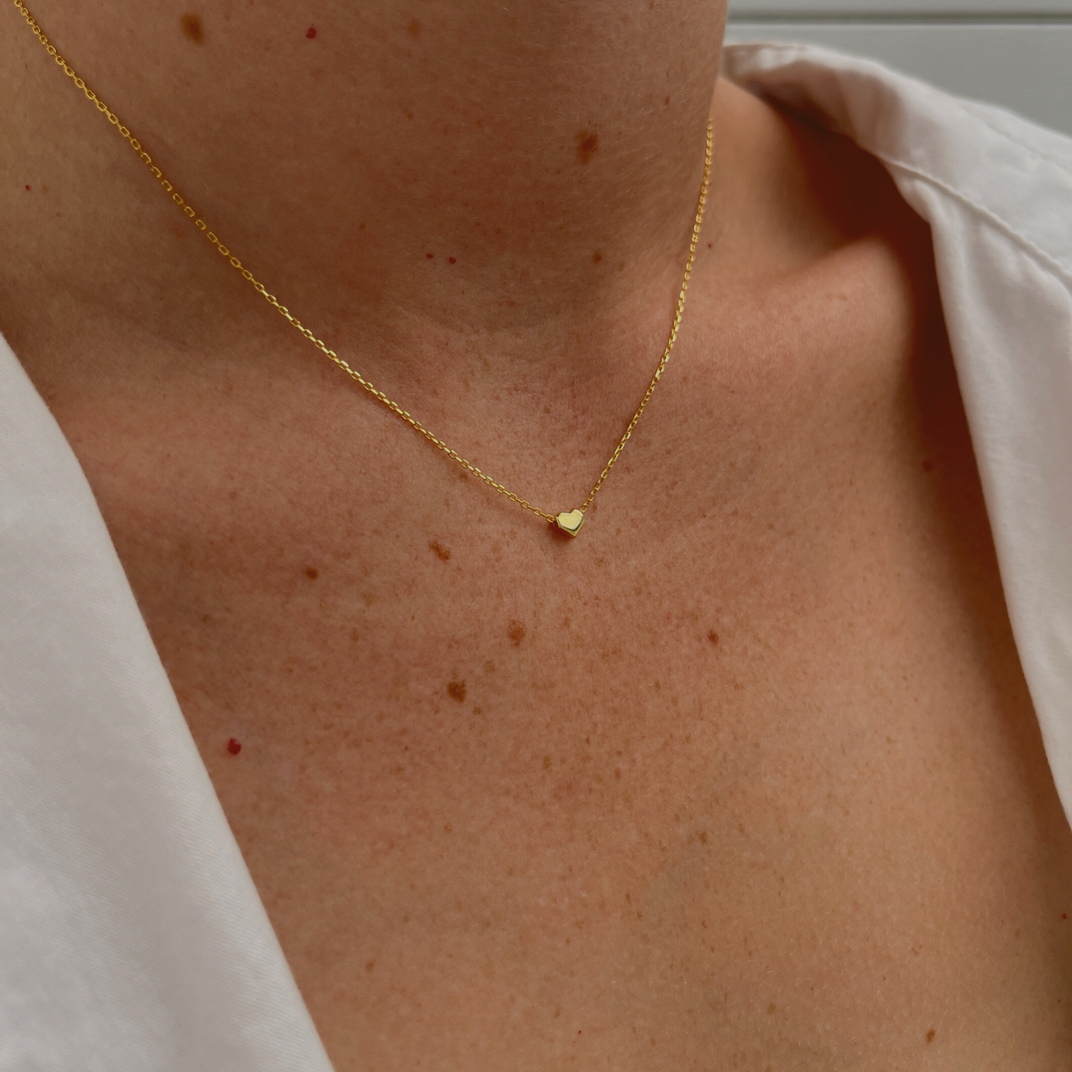 Woman adorned with the 'Amore' necklace featuring a 14K gold-plated heart pendant