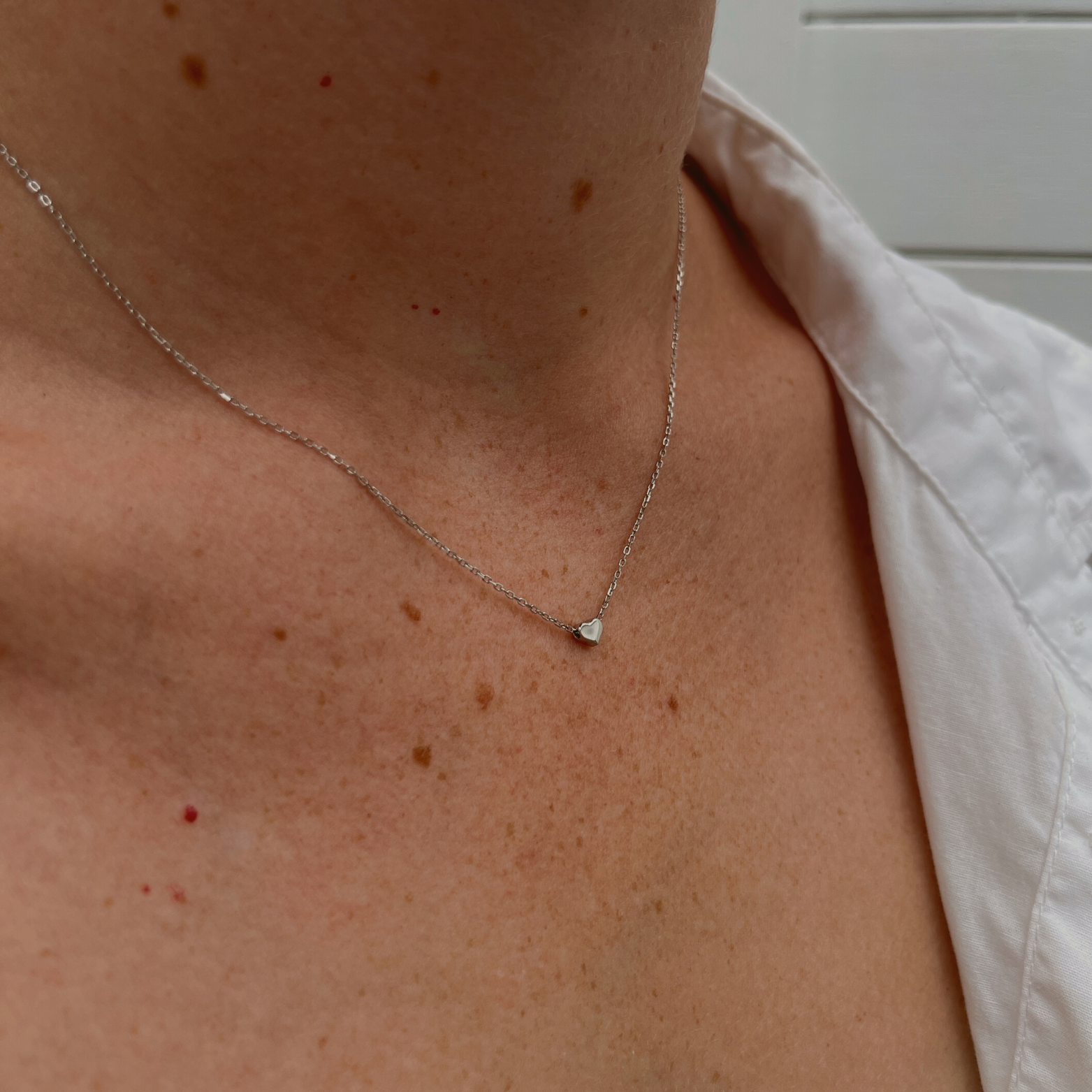 A woman adorned with the Amore sterling silver necklace featuring a heart pendant