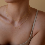 Woman adorned with a petite initial necklace in 14k vermeil