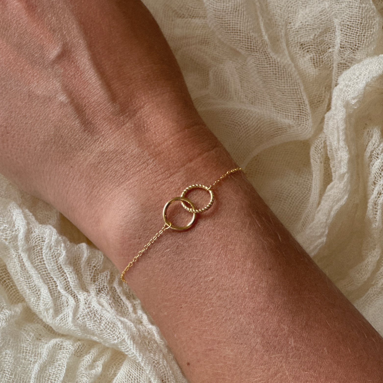 Close-up of a 14K gold-plated interlock bracelet on a woman's wrist