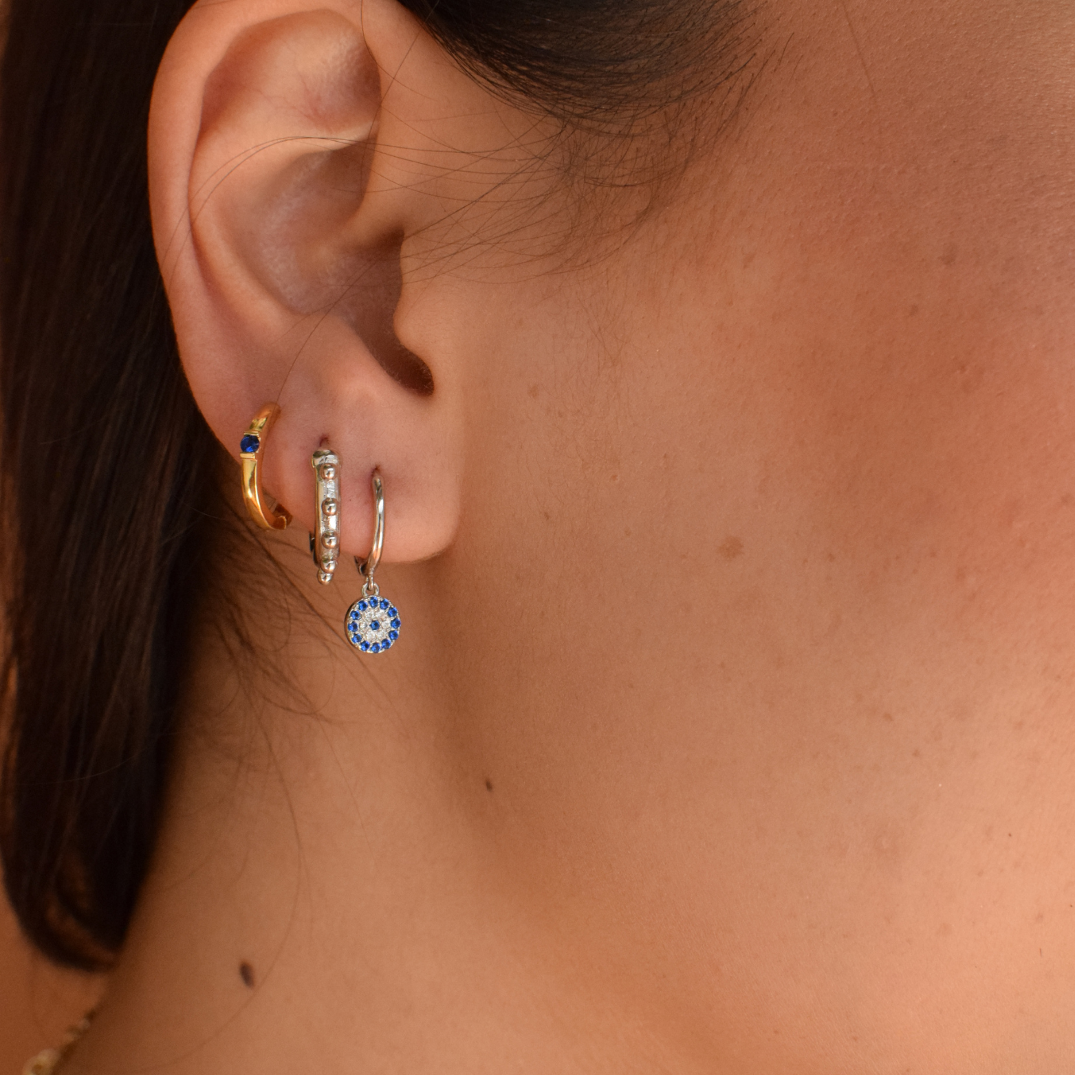Close-up of a woman showcasing her Blue Chloe Hoops in 14K gold plating