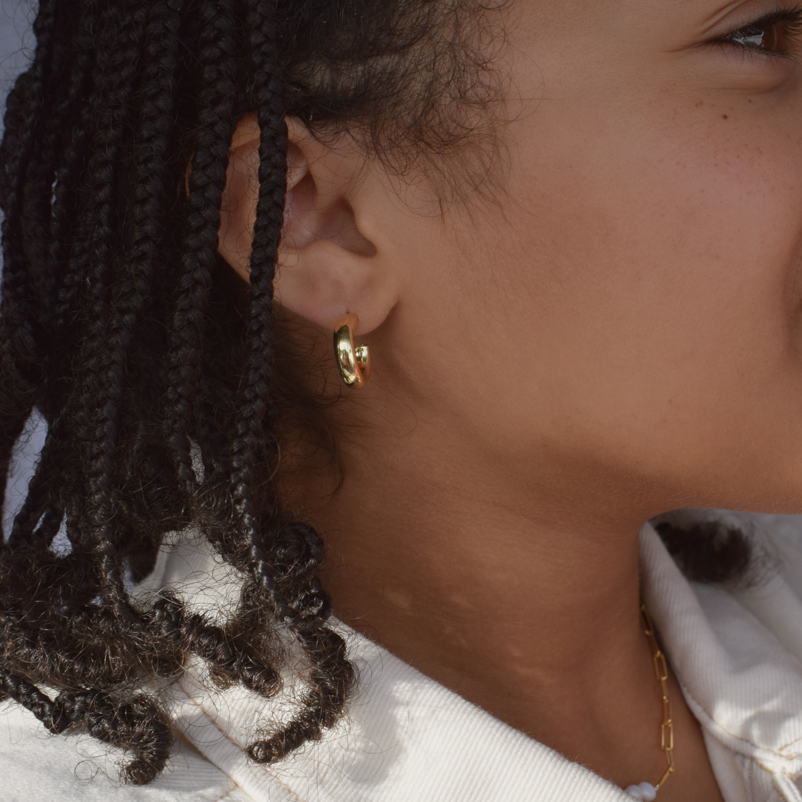 Close-up of a young woman with braids showcasing the Charlotte Hoops - 14K Gold Plated
