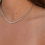 Close-up of a woman's neck adorned with a sterling silver graduating tennis necklace