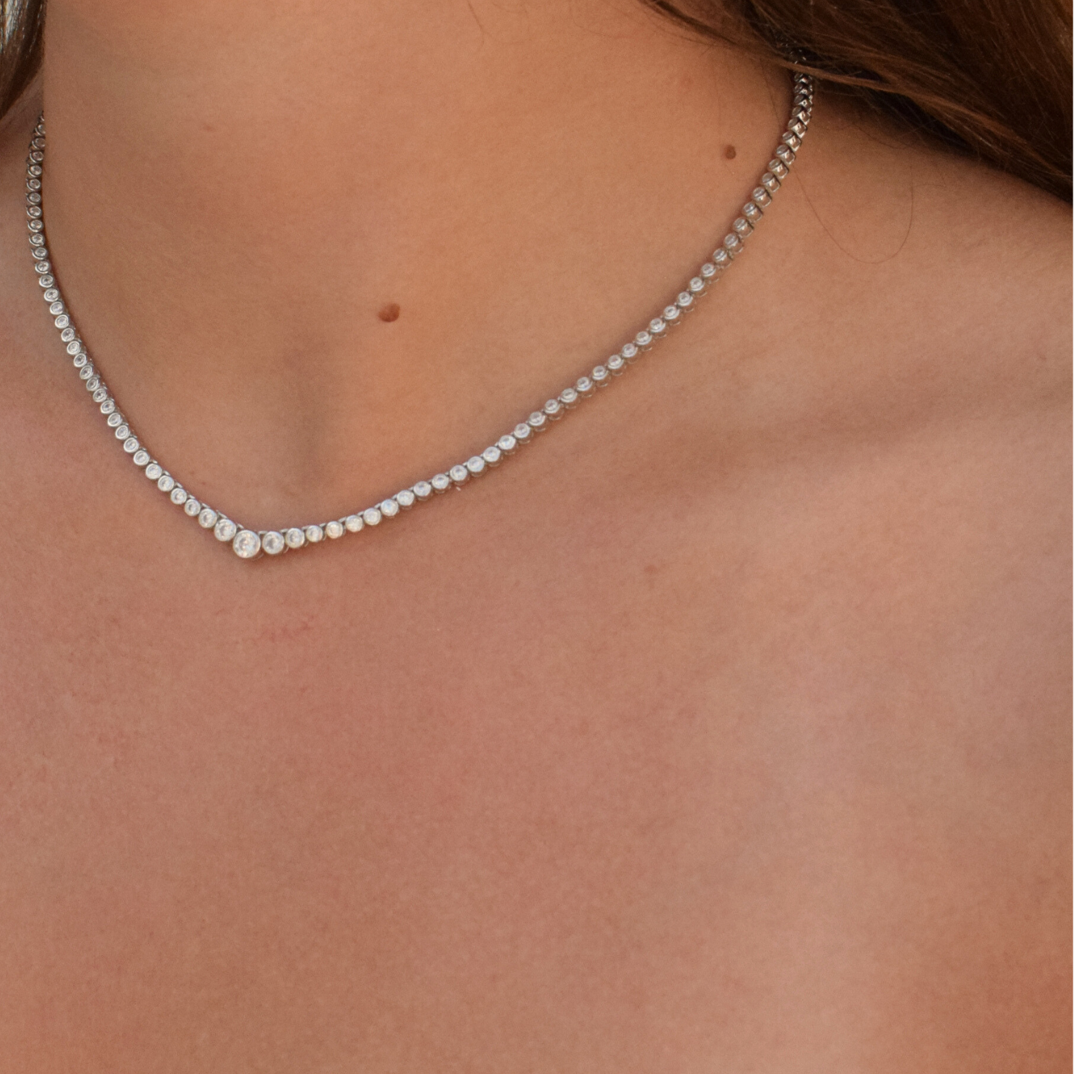 Close-up of a woman's neck adorned with a sterling silver graduating tennis necklace