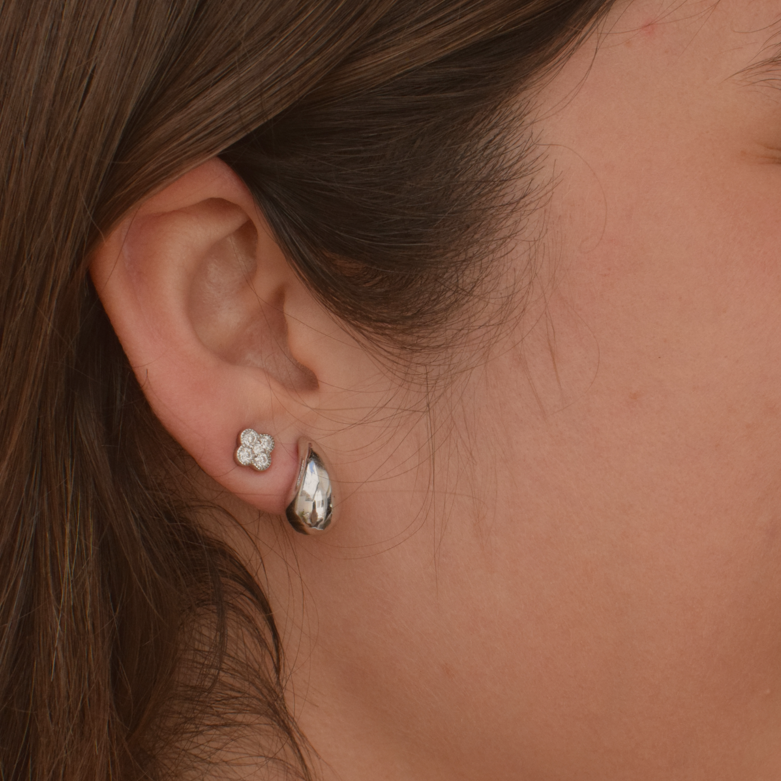 Close-up of sterling silver clover stud earrings worn by a woman
