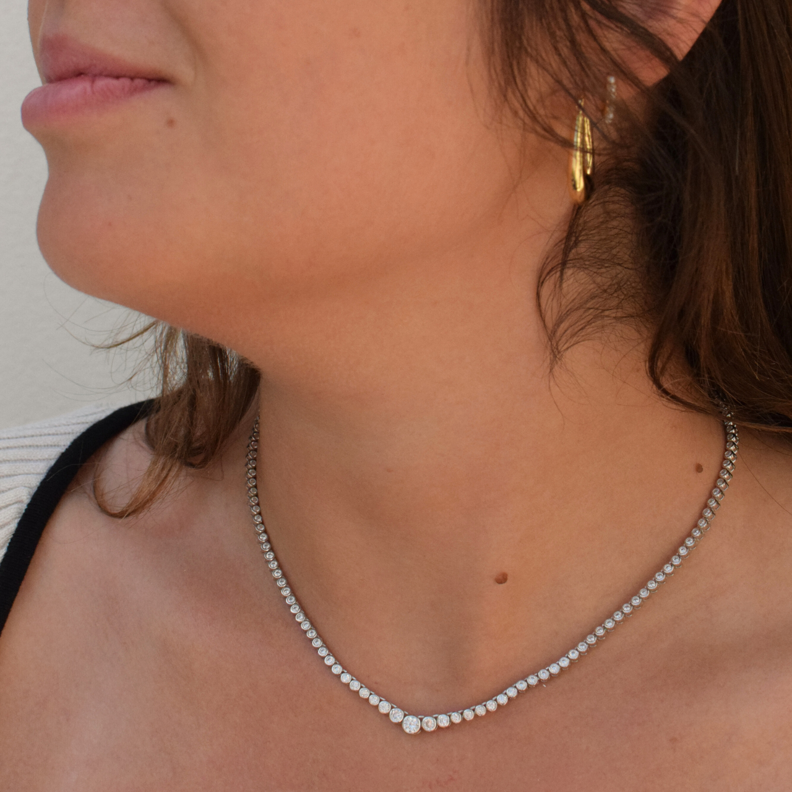 Detail shot of a graduating tennis necklace made of sterling silver with diamonds on a woman's neck