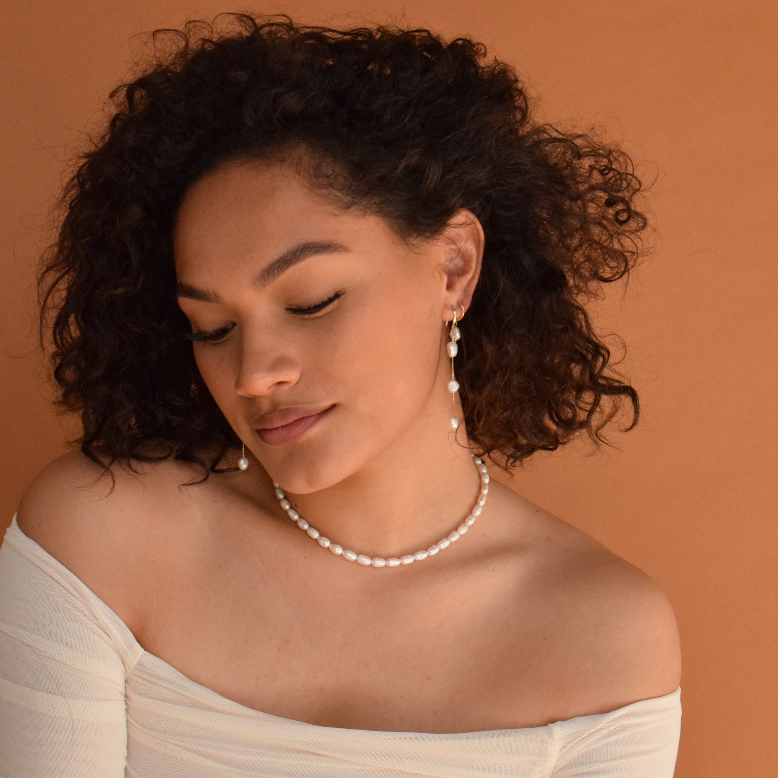 Close-up of Baroque Hoops - 14K Gold Plated as worn by a woman with curly hair