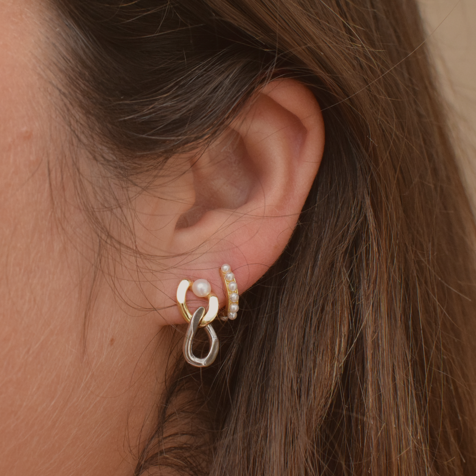 Side angle of two-tone pearl studs being worn