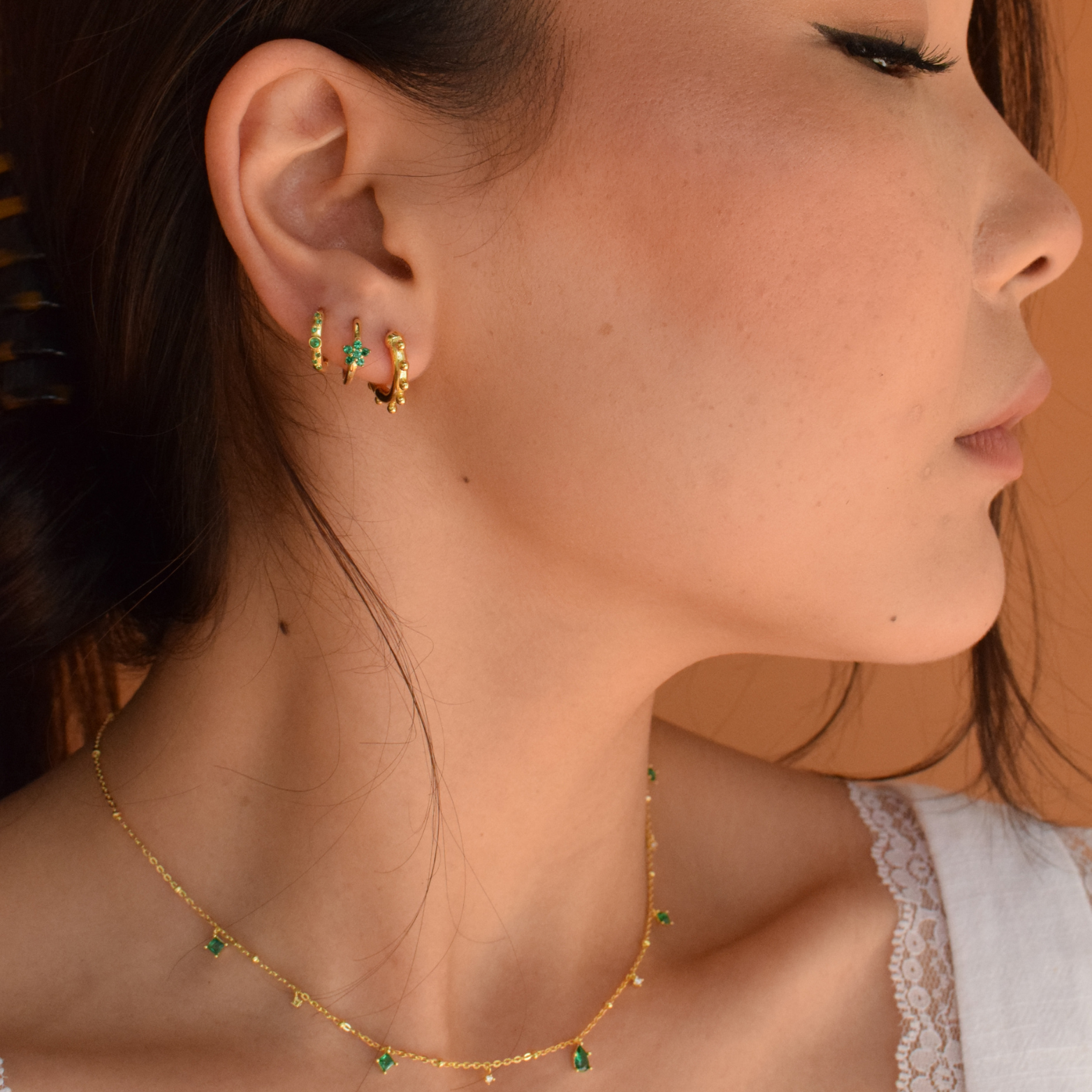 Close-up of Green Logan Hoops earrings on a model with no necklace
