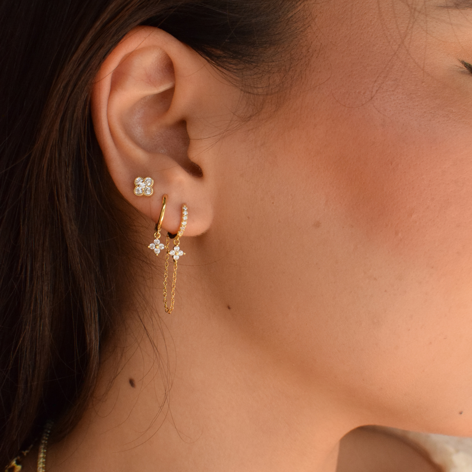 Close-up of a clover-shaped 14K gold plated earring on a woman's ear