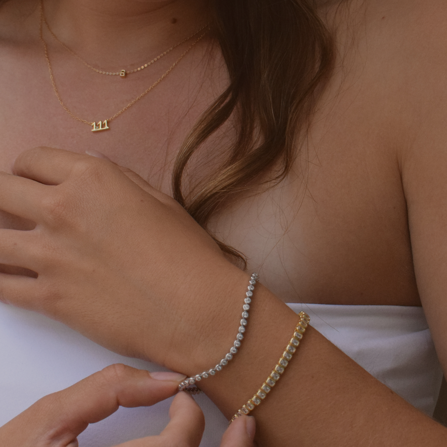 Detail of a 14K gold plated Baguette Tennis Bracelet with diamond accents worn by a woman