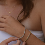 A close-up of a sterling silver tennis bracelet worn on a woman's wrist