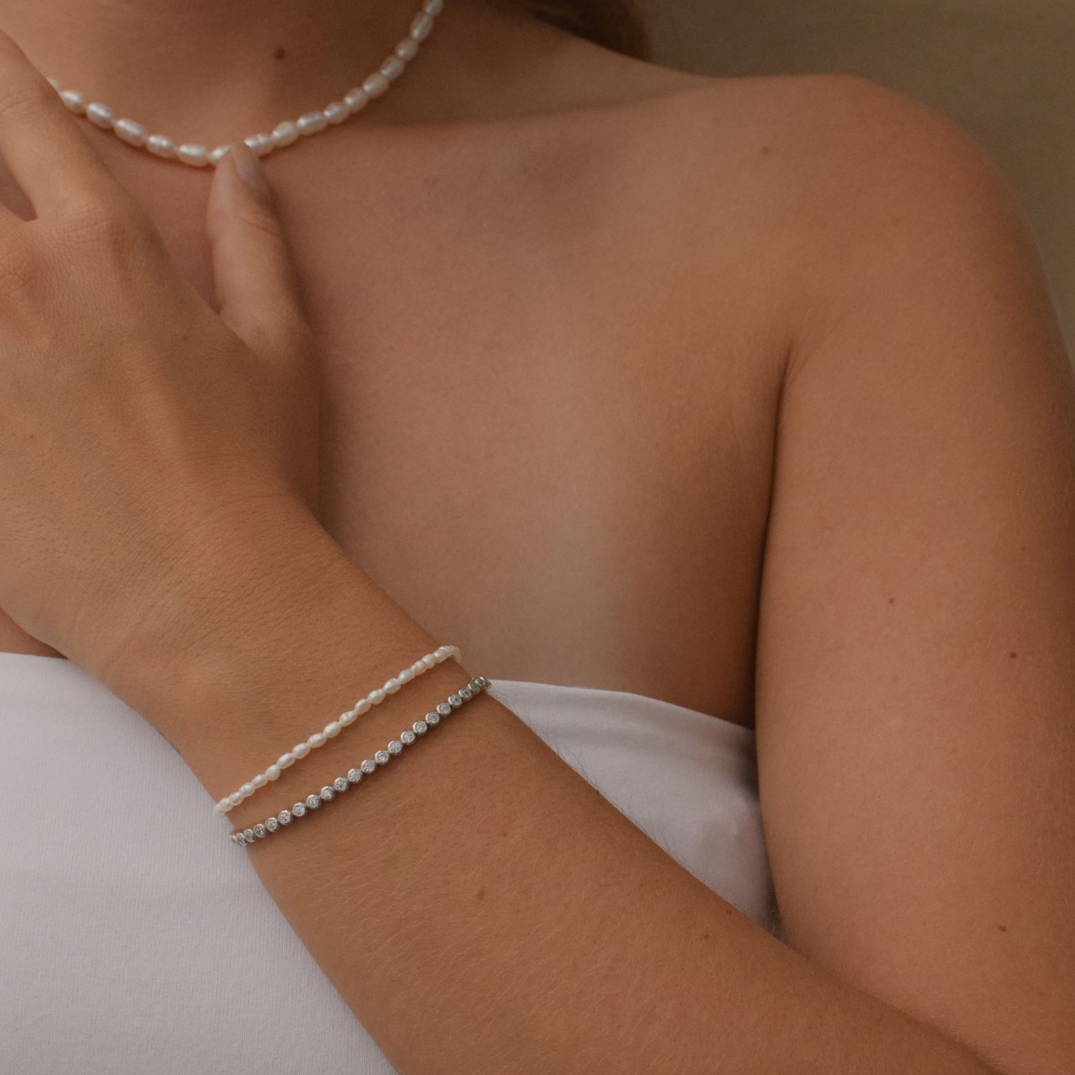 A sterling silver tennis bracelet presented against a white fabric background