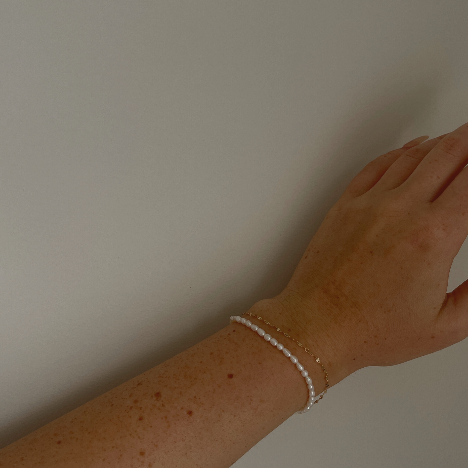 Hand model showcasing the Amalfi Pearl Bracelet with its 14K gold-plated design