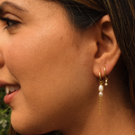 Close-up of a woman wearing one Grace Hoop earring in 14K gold plating